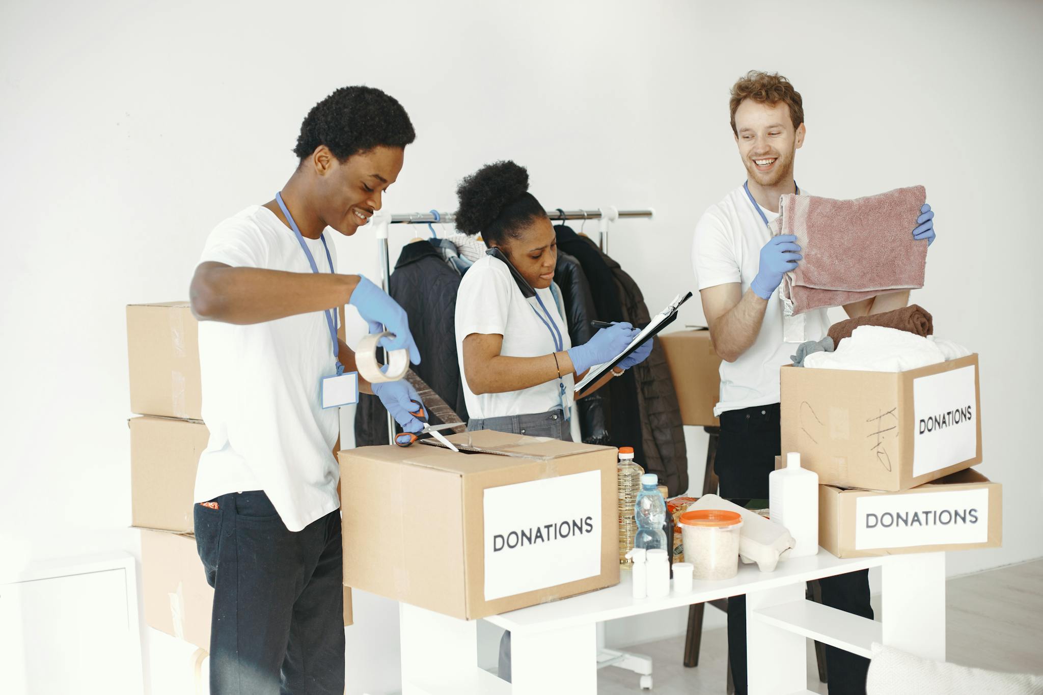 Diverse volunteers happily sorting donation boxes indoors during a charity event.