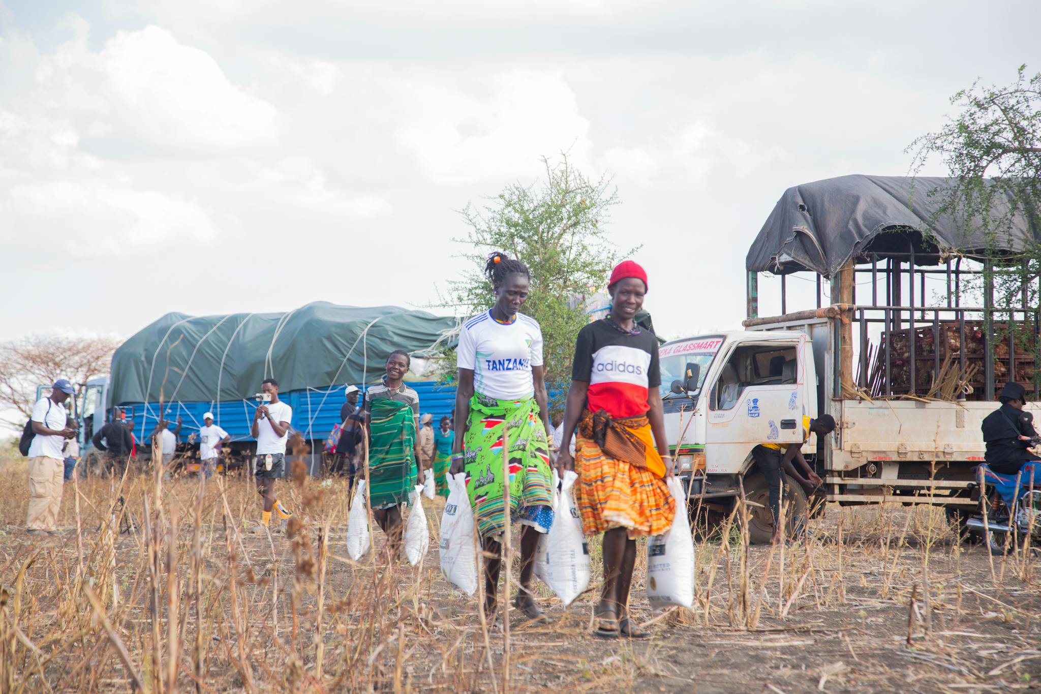 Women participate in a community aid distribution event in a rural setting.